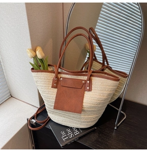 Close-up of large straw tote bag featuring brown leather pocket and rivet details