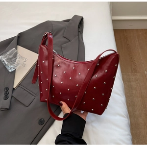 Close-up of red glossy hobo bag with silver studs and crescent moon shape design