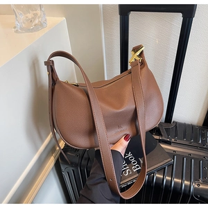 Detail of brown litchi pattern leather shoulder bag with gold X-shaped metal hardware