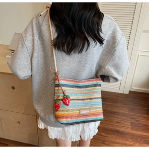 Détail du sac en paille tissée à rayures colorées avec pendentifs fraises rouges