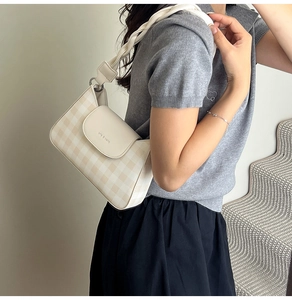 Detail of checkered shoulder bag with wide woven strap and embossed flap closure