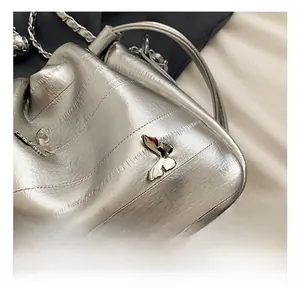 Détail d'un sac seau argenté métallisé avec ornement en forme de papillon en métal