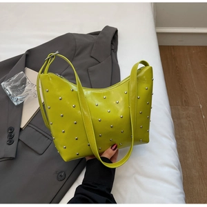 Detailed view of neon green dumpling bag with silver studs on a grey blazer