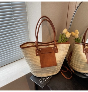 Detail of straw woven tote bag with brown faux leather handles in a warm interior setting
