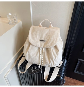 Detail of minimalist beige canvas backpack on a suitcase for stylish travel and commuting