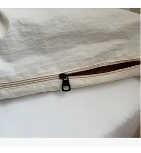 Close-up of smooth black metal zipper detail on white canvas travel bag fabric