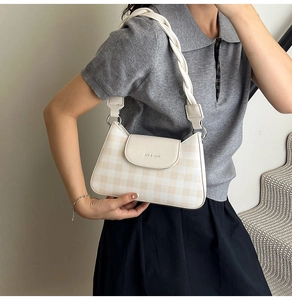 Detail of checkered shoulder bag featuring woven leather strap and metal hardware