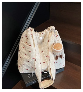Close-up of cream mesh tote bag with red bow print and a cute coffee cup plush charm