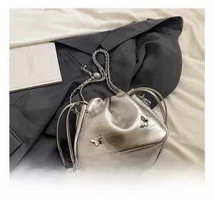 Détail de la bandoulière chaîne argentée et des breloques papillon sur le sac texturé