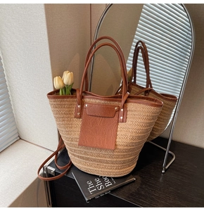Detail of straw tote bag showing fine woven texture and premium brown leather handle
