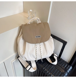 Detail of contrast-color backpack featuring beige body, khaki flap, and secure drawstring closure