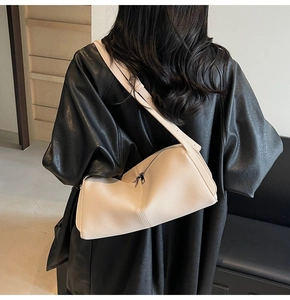 Close-up of cream pebble leather shoulder bag with sleek dual strap and metallic zipper