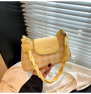 Detail of yellow checkered faux leather bag with unique twisted woven handle and engraving