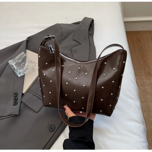 Detail of dark brown glossy moon bag with silver rivets and adjustable shoulder strap