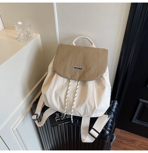 Close-up of a stylish cream nylon backpack with khaki flap on a suitcase