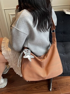 Brown woven hobo tote bag with silver star charm shown on model in casual minimalist style