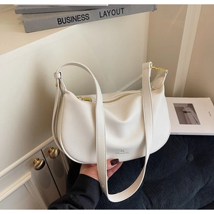Close-up of white crescent crossbody bag featuring lychee grain leather and gold zipper