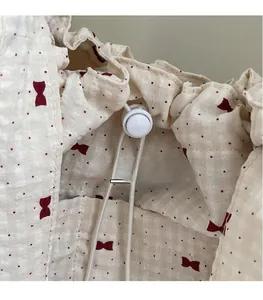 Detailed macro view of cream fabric bag with red bow pattern and white drawstring closure