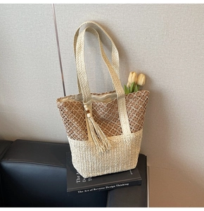 Detail of woven straw tote bag with dual-texture knit, fringe beads, and tulip decoration