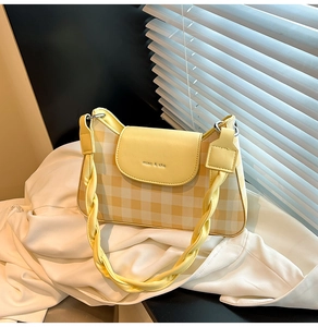 Close-up of yellow checkered canvas crossbody bag with woven leather shoulder strap