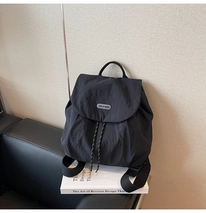 Detail view of a black nylon backpack featuring a drawstring closure and brand logo