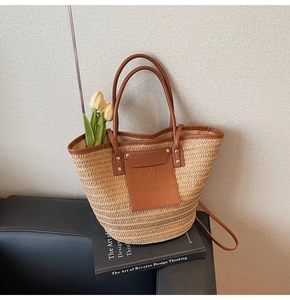 Detail of woven straw tote bag with brown leather trim and front pocket accents