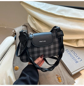 Detail view of a vintage plaid crossbody bag with leather flap and woven shoulder strap