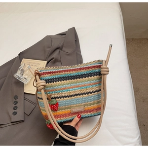 Détail du sac seau tissé à rayures multicolores avec breloques fraises et étiquette en cuir