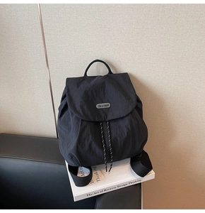Close-up of black nylon backpack with drawstring closure and You Ji Bear metal logo plate