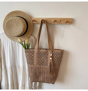 Detail of woven straw tote bag with mesh texture and wooden bead tassel for beach vacation