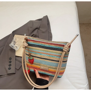 Détail d'un sac seau en paille tissée colorée avec rayures et breloques fraises