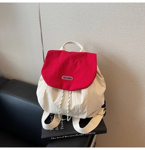 Detail of red and cream nylon backpack showing woven strap and brand logo patch