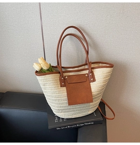 Detail view of woven straw tote bag with brown leather trim on a sofa background