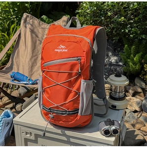 Close-up of orange outdoor backpack with gray mesh straps and elastic compression cords