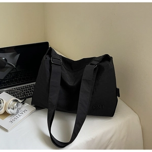 Détail d'un grand sac fourre-tout noir avec bandoulière réglable sur un bureau minimaliste