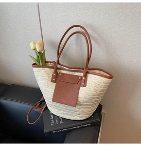 Detail of hand-woven straw tote bag with brown leather trim and white tulip accents