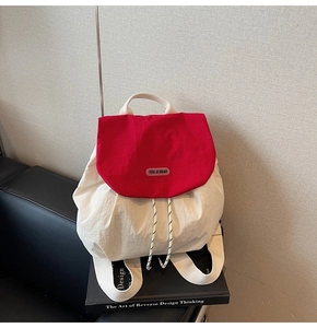 Detail of red and white backpack with drawstring closure and brand logo on flap