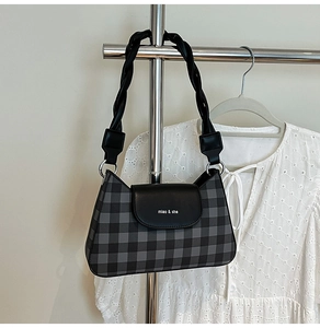 Detail of checkered baguette bag with miao & she logo and braided leather shoulder strap