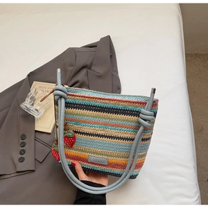 Détail d'un sac seau en paille tissée avec rayures colorées et breloques fraises