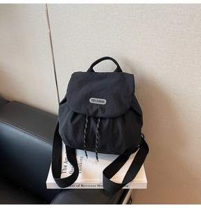 Detailed view of the black nylon backpack featuring a drawstring closure and logo patch