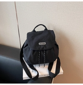 Detail of minimalist black nylon backpack featuring drawstring closure and silver brand logo