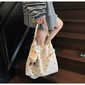 Detail of cream tote bag with red bow pattern and cute coffee cup plush charm