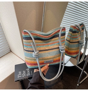 Détail du sac seau tissé à rayures colorées avec écusson logo en cuir et anses en corde bleue