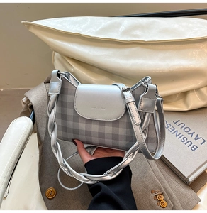 Detail of silver plaid crossbody bag with metallic flap and woven shoulder strap
