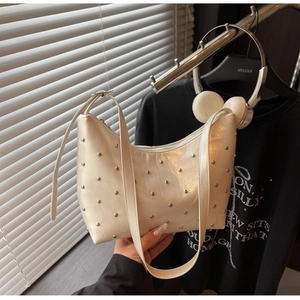 Detail of creamy white crescent hobo bag with silver studs and smooth leather texture