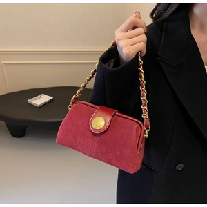 Detail of red velvet doctor bag featuring a golden chain and animal relief clasp