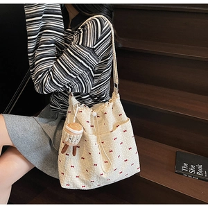 Detail of off-white canvas tote bag with red floral bows and a cute cake plush pendant