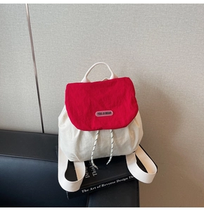 Detail of red and cream canvas backpack featuring brand logo and drawstring closure