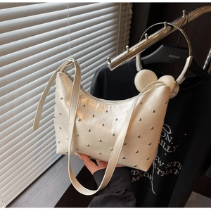 Close-up of white glossy leather crescent bag with silver stud rivets and top zipper detail