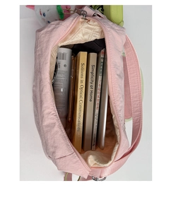 Detail showing the spacious interior of a pink nylon tote bag with books and a tablet